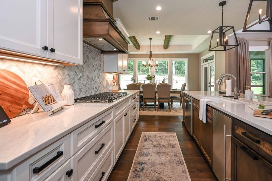 Modern kitchen with white cabinets, wood beams, and a view of a dining room.