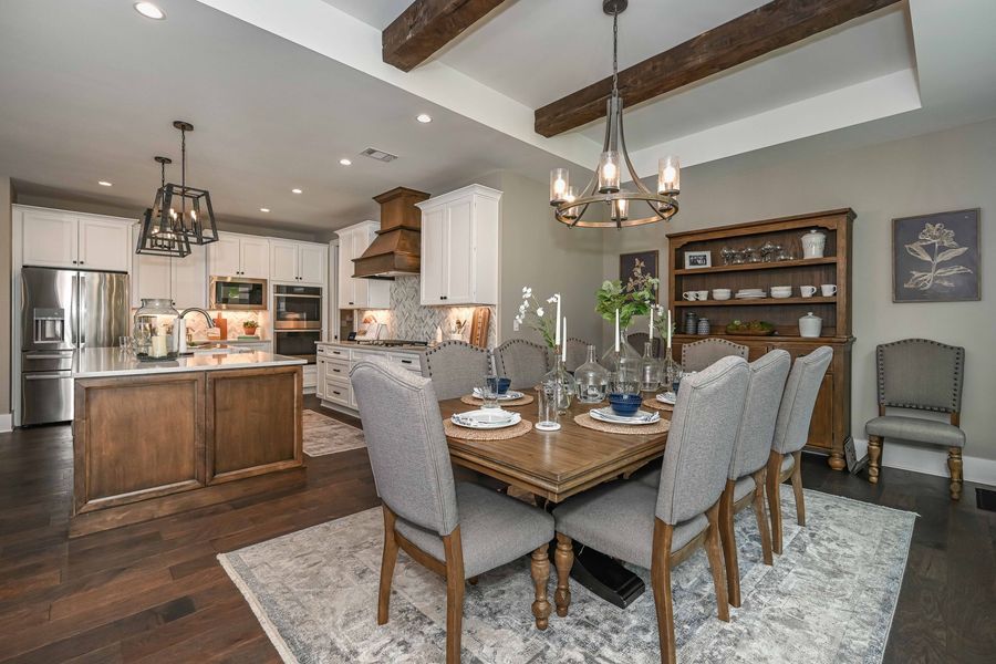 Open-concept kitchen and dining room with wood floors, white cabinets, and a dining table set for dinner.