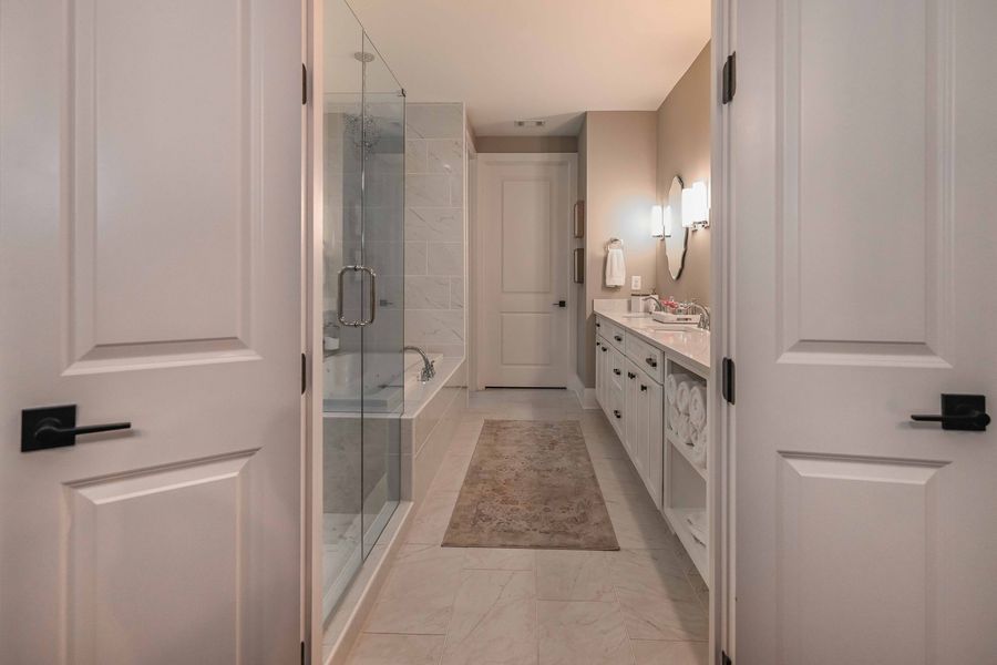 Bathroom with glass shower, white vanity, and two white doors.