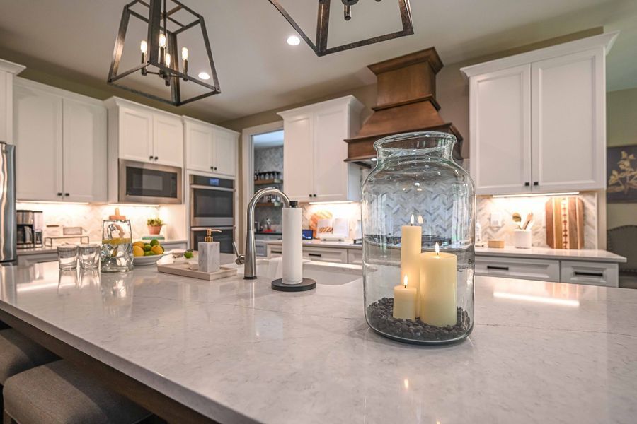 Modern kitchen with white cabinets, marble countertops, and a copper range hood.