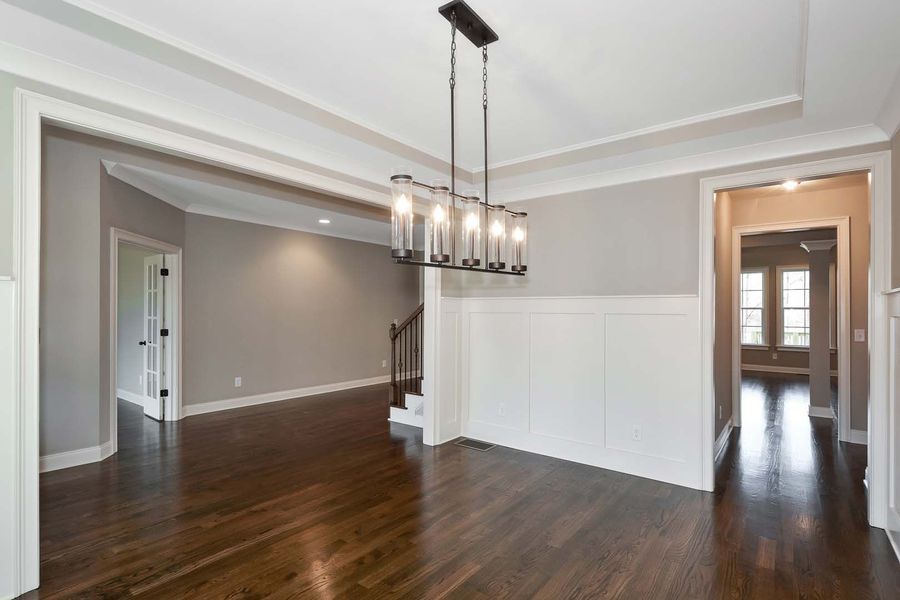 Dining room with dark wood floors, gray walls, white trim, and a modern chandelier.