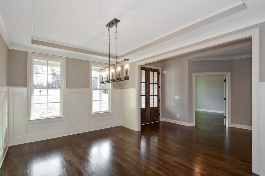 Dining room with dark wood floors, windows, and a chandelier.