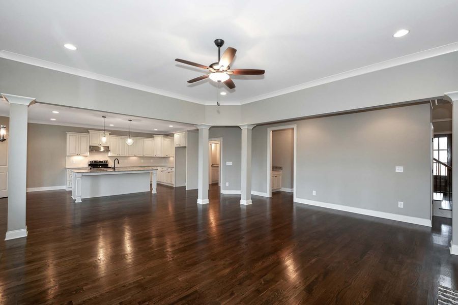 Spacious, modern living room with dark wood floors, light gray walls, and open kitchen.