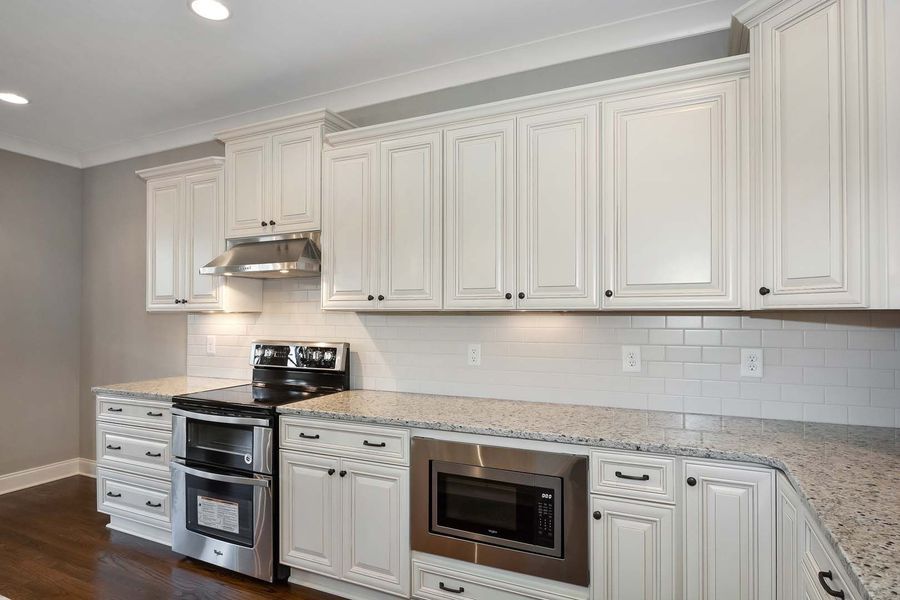 White kitchen with granite counters and stainless steel appliances.