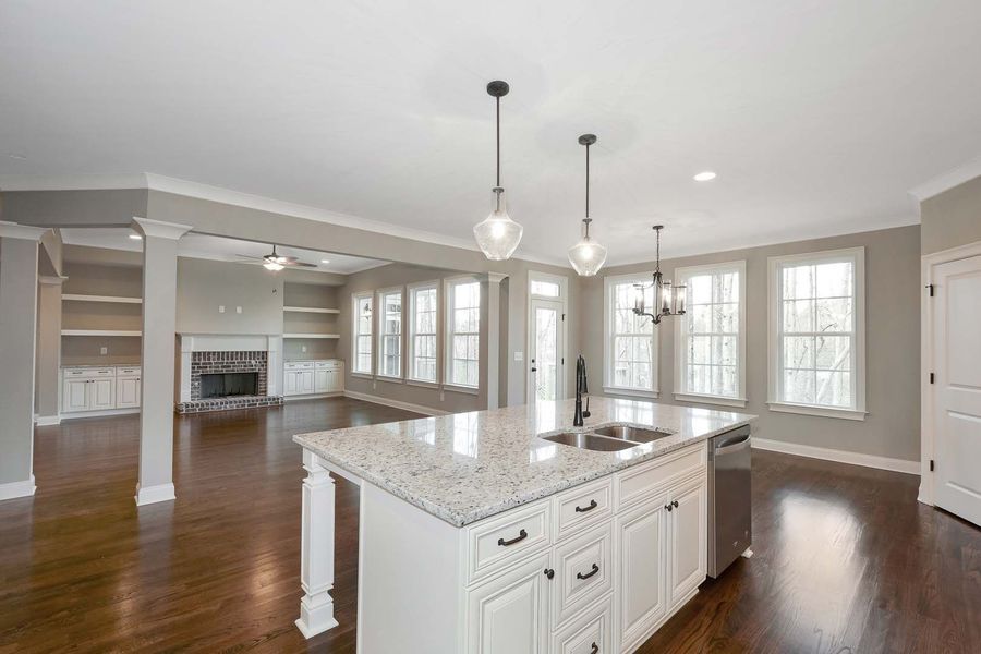 Spacious open-concept kitchen with white island, granite countertop, and dark wood floors.