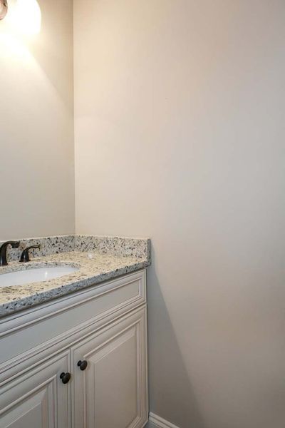 White vanity with granite countertop and black fixtures in a bathroom.