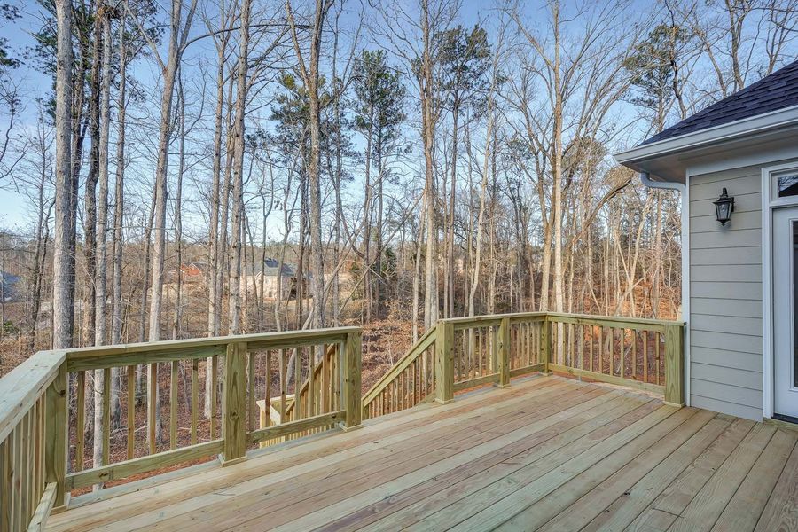 Wooden deck overlooking a wooded area and a house.