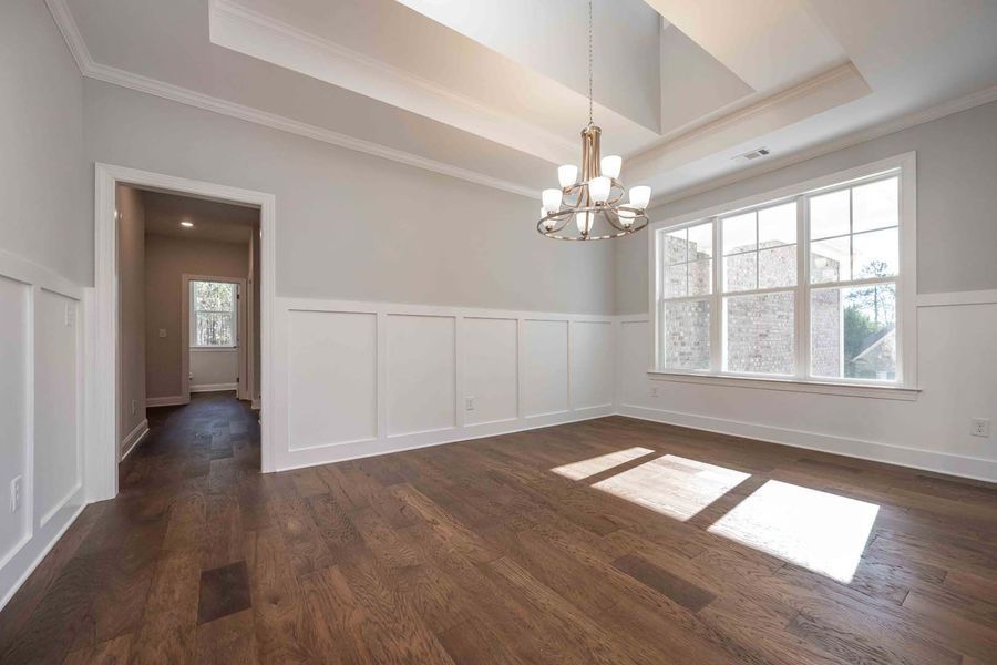 Empty, bright dining room with hardwood floors, white walls, a chandelier, and a large window.