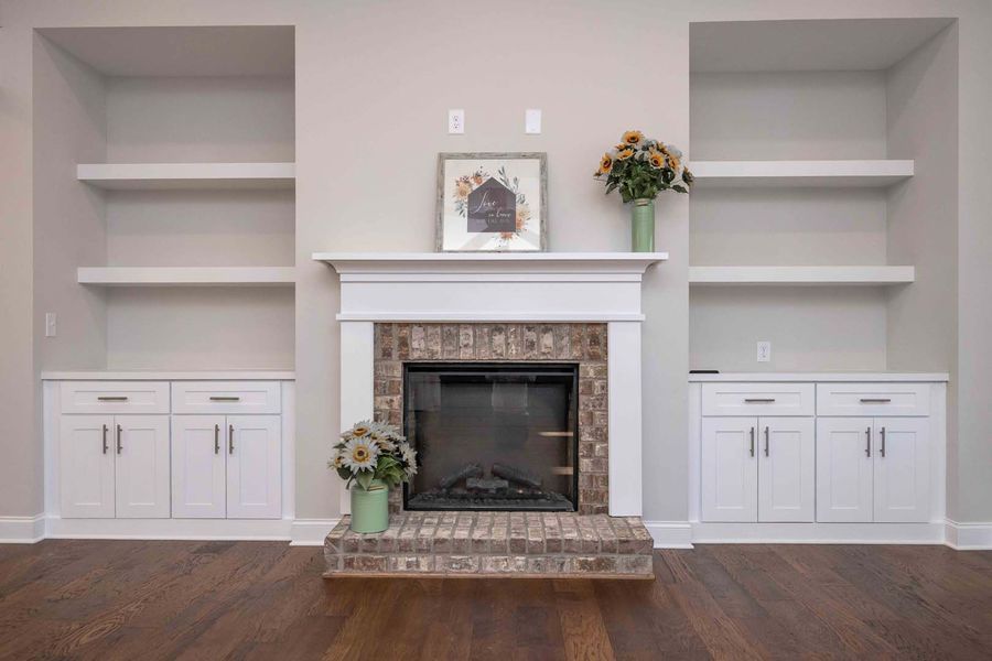 Fireplace with white built-ins, shelves, and cabinets on either side. Sunflowers are on the mantel and on the hearth.