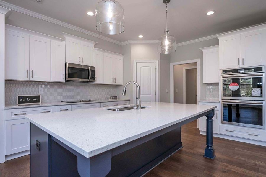 White kitchen with large island and dark blue base; stainless steel appliances.