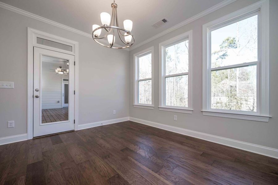 Empty dining room with hardwood floors, windows, and chandelier.
