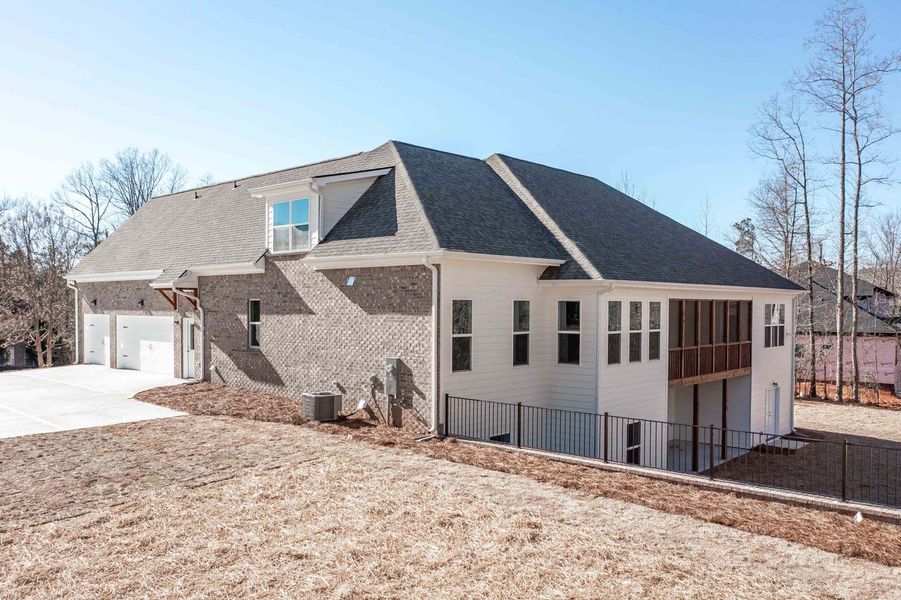 House with brick and white siding, black roof, three-car garage, and a screened porch.