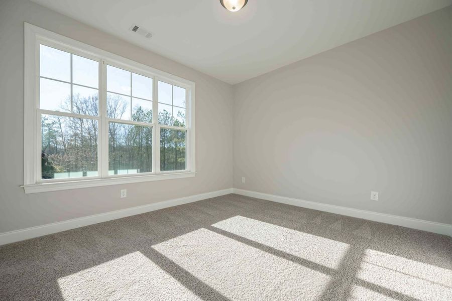 Empty room with large window, beige carpet, and light gray walls.