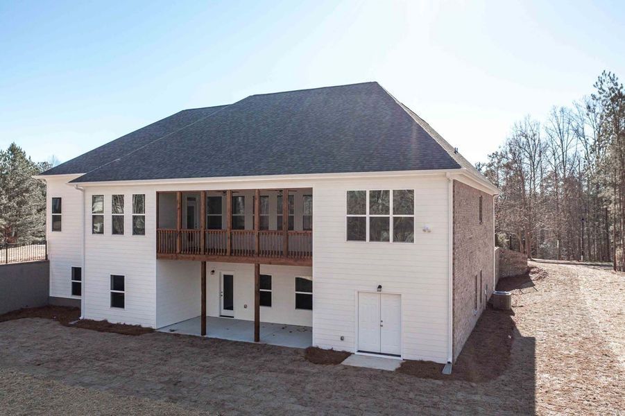 White two-story house with a screened porch, set in a wooded area.