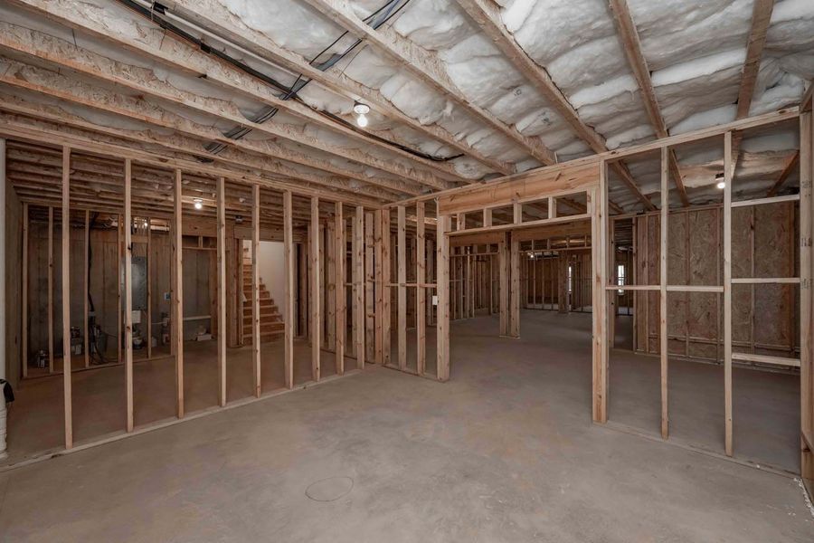 Framed wooden walls in a basement under construction; concrete floor, exposed joists, and insulation.