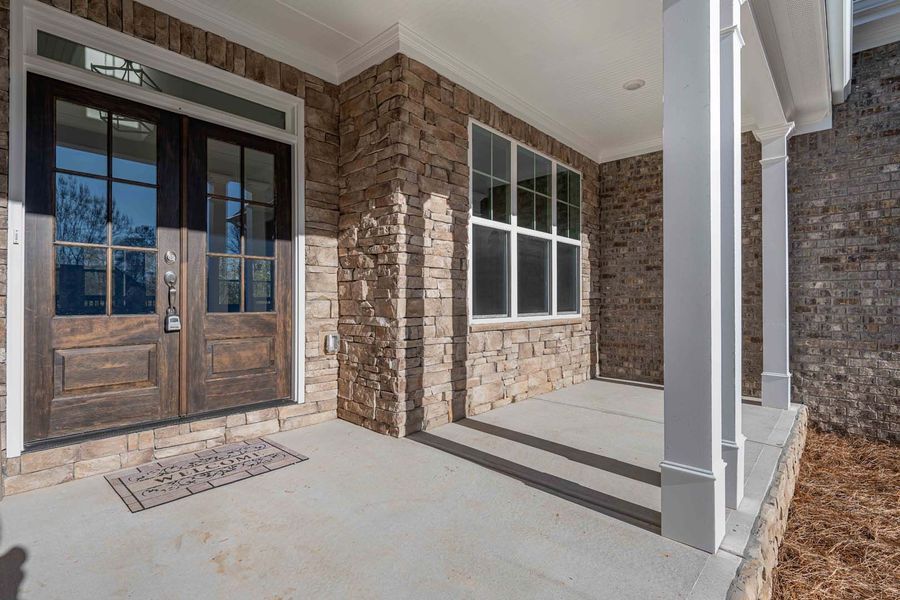 Front porch with stone facade, double doors, and white columns.