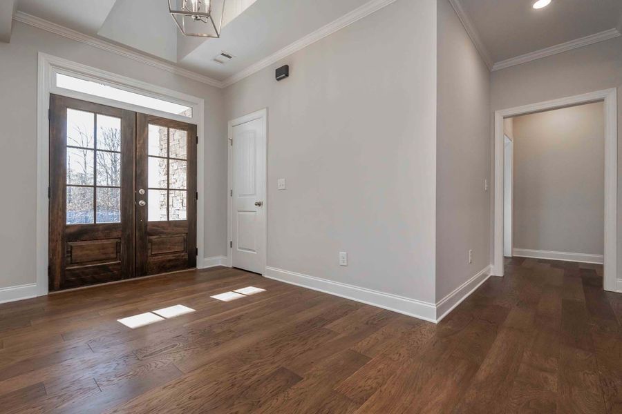 Wooden double doors lead into a room with hardwood floors and white walls.