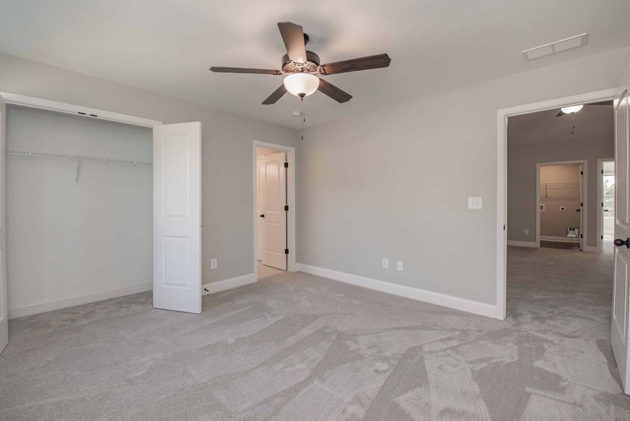 Empty bedroom with gray walls, carpet, and a ceiling fan.