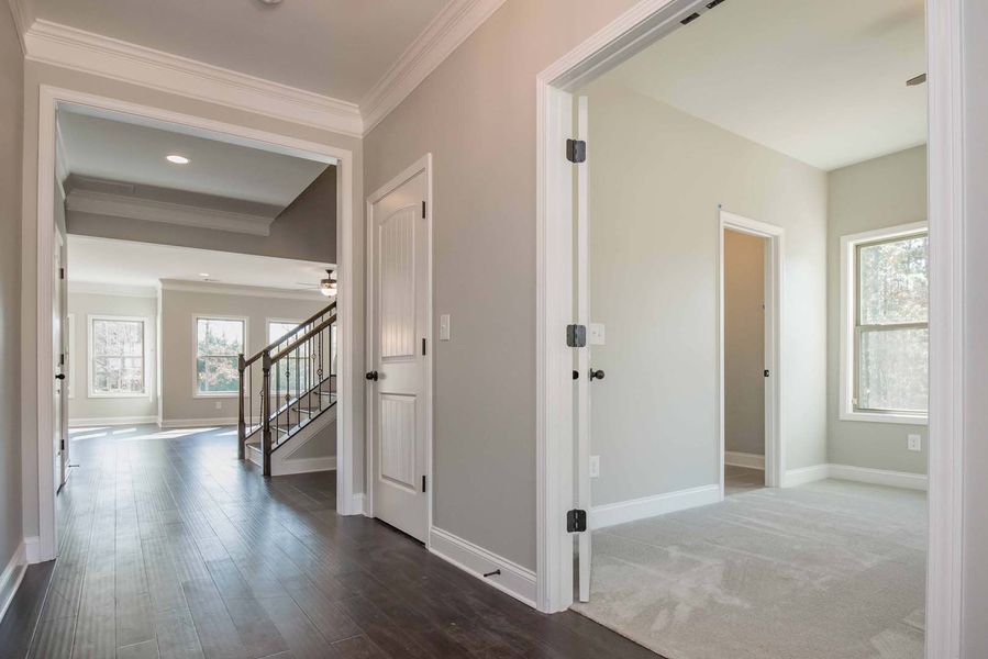Hallway with dark wood floor, light gray walls, and doorways leading to rooms.