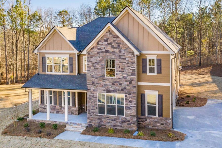 Two-story house with stone and tan exterior. Front porch, dark roof, windows with shutters.