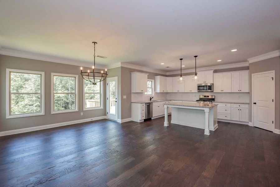 Spacious, open-concept kitchen and living area with white cabinets, island, and dark wood floors. 