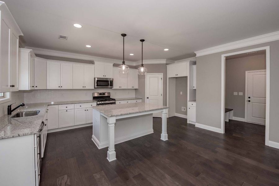 Modern white kitchen with island, dark wood floor, gray walls.