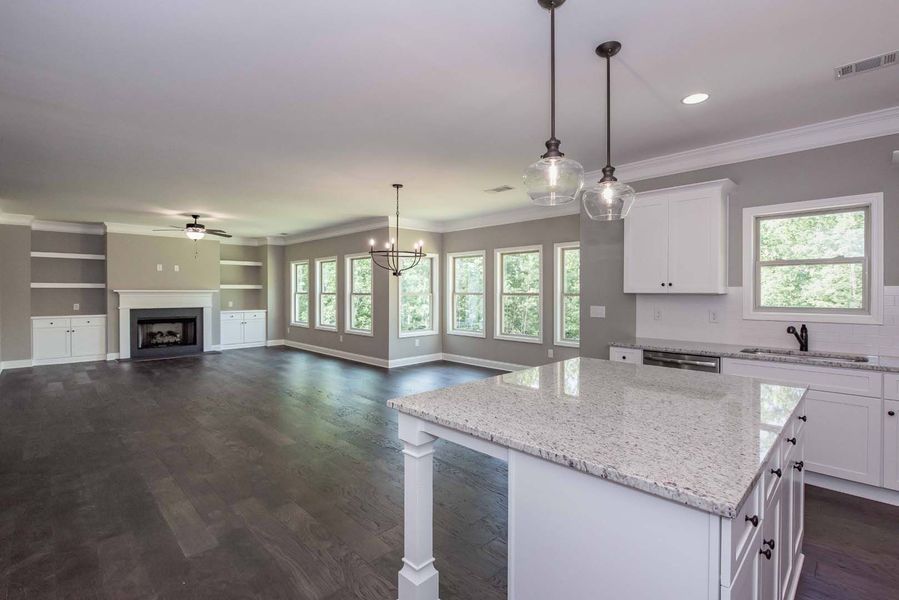 Open-concept kitchen and living area with white cabinets, gray walls, and hardwood floors.