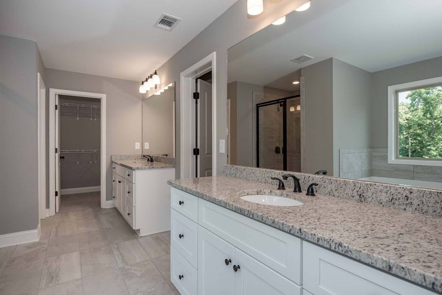 Bathroom with white cabinets, gray countertops, large mirror, and a window.