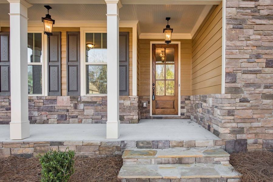 Front porch with stone facade, brown door, and two hanging lights.