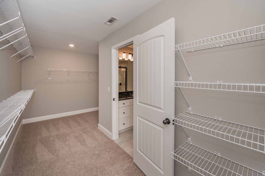 Walk-in closet with wire shelving and a doorway leading to a bathroom with a vanity.