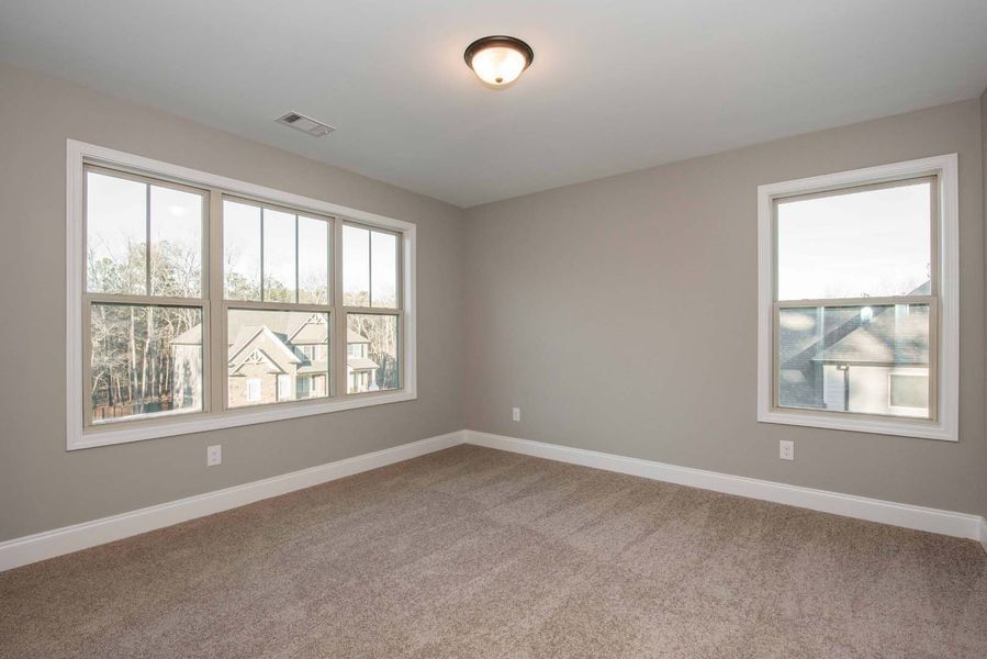 Empty room with beige carpet, gray walls, and two windows with white trim.