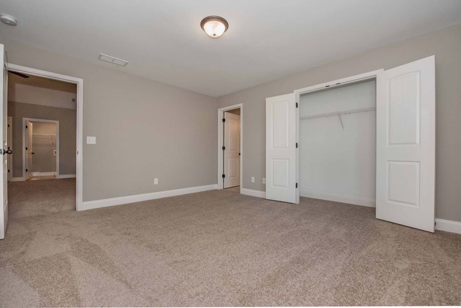 Empty bedroom with gray walls, beige carpet, white doors, and a closet.