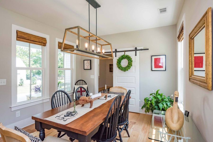 Dining room: wooden table with chairs, sliding barn door, and a chandelier.