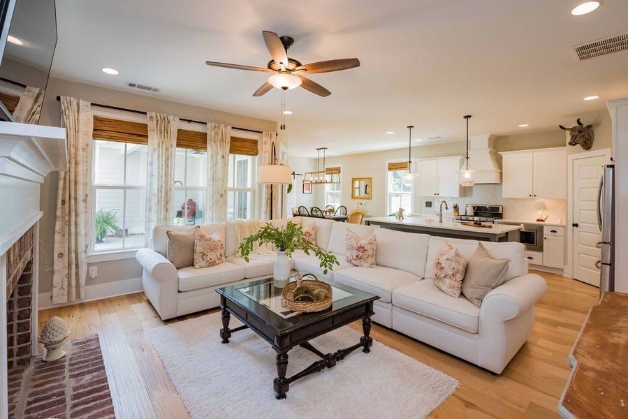 Living room with white sofas, fireplace, open to kitchen.