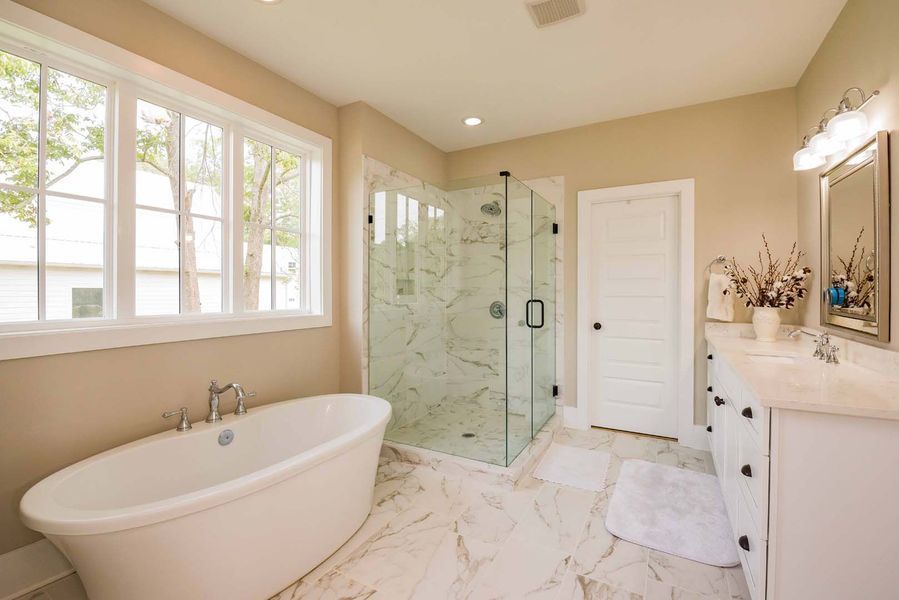 Bathroom with a white tub, glass shower, double sink, and large window.