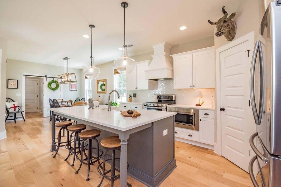 Spacious kitchen with gray island, white cabinets, wooden floor, and deer head decor.