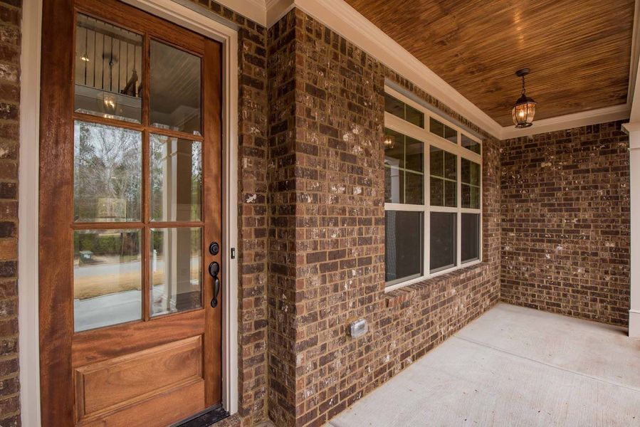 Brick entryway with wooden door, window, and porch ceiling.