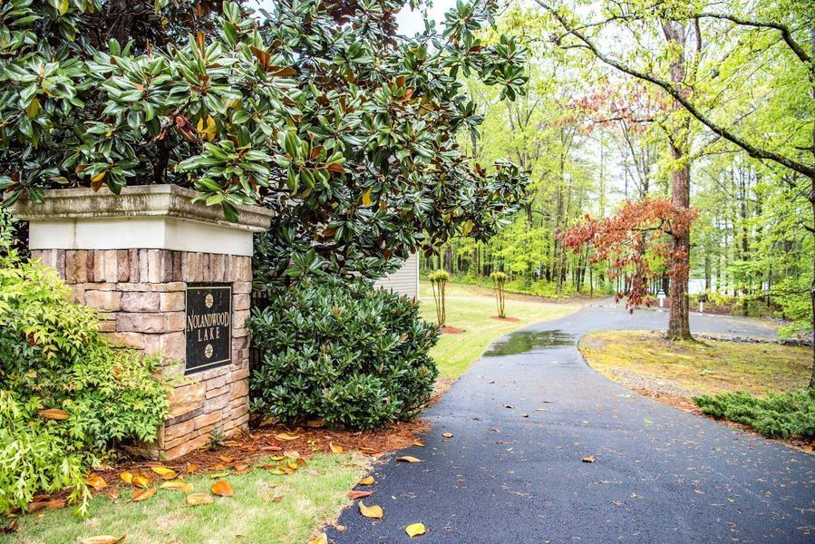 Brick entrance with sign for Hanover Hall, surrounded by greenery, leading to a paved road lined with trees.
