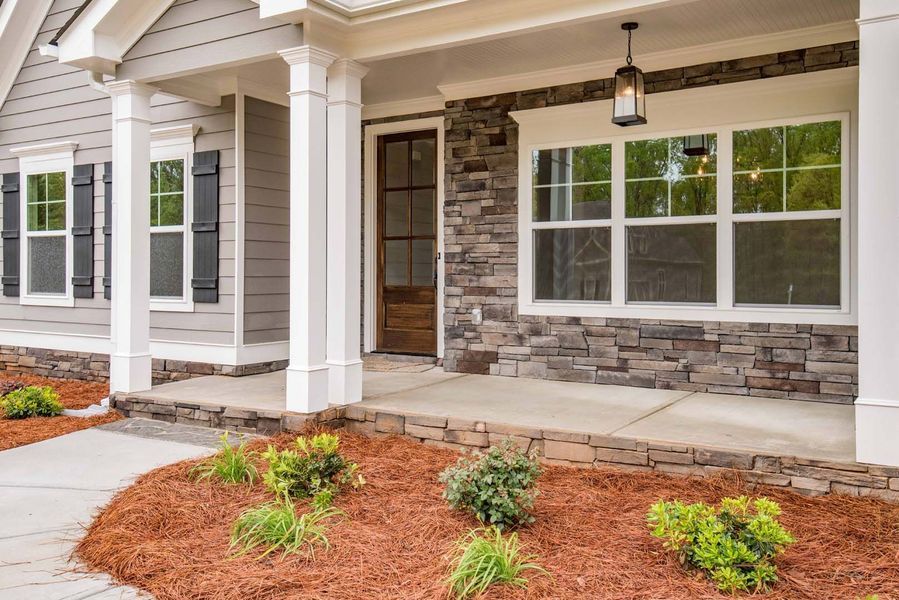 House exterior with a stone facade, porch, and garden.