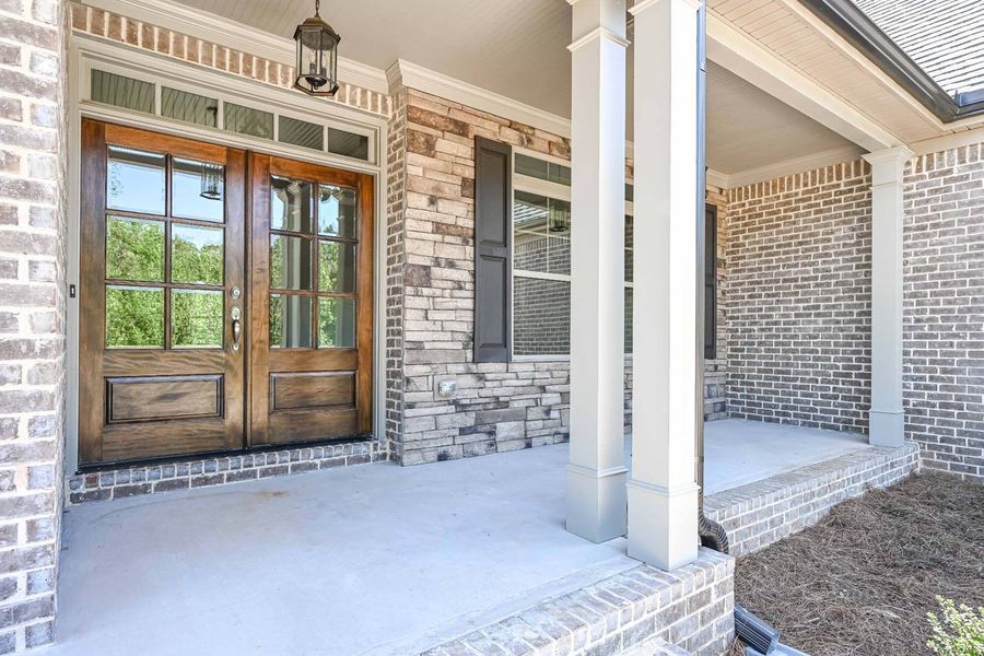 Front porch with double wooden doors and brick facade.