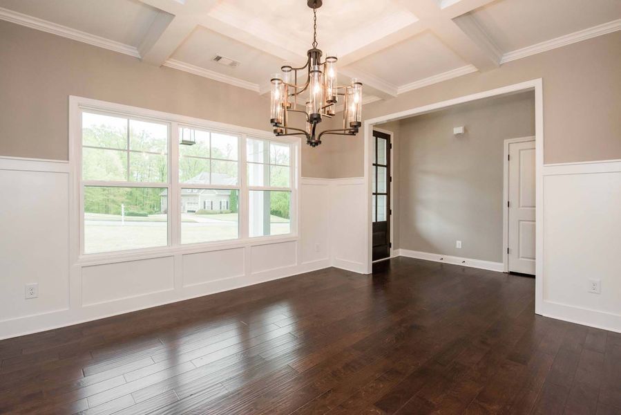 Dining room with hardwood floors, large windows, chandelier, and white wainscoting.