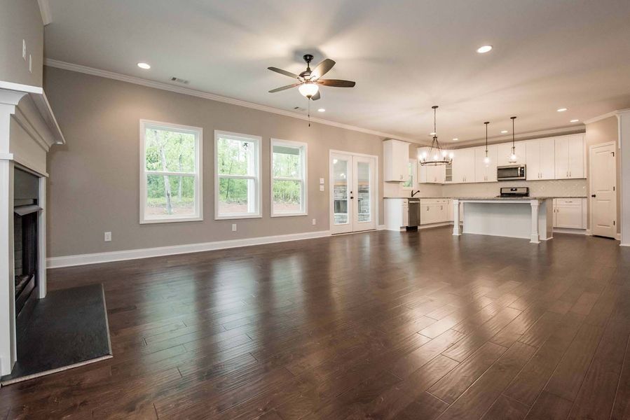 Spacious, open-concept living space with fireplace, kitchen island, and hardwood floors.