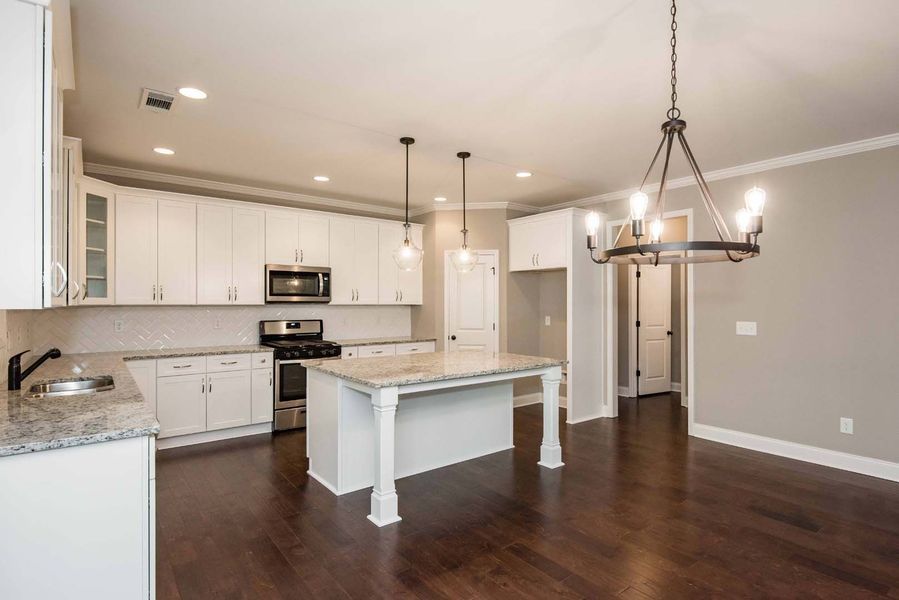 Modern kitchen with white cabinets, granite countertops, and a dark wood floor.