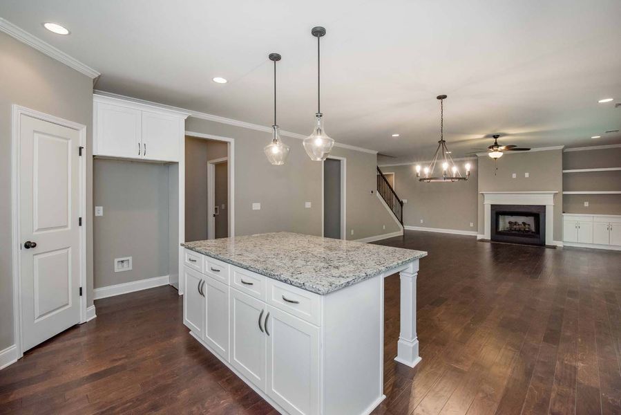 Kitchen with white cabinets, gray walls, granite island, and dark wood floors.
