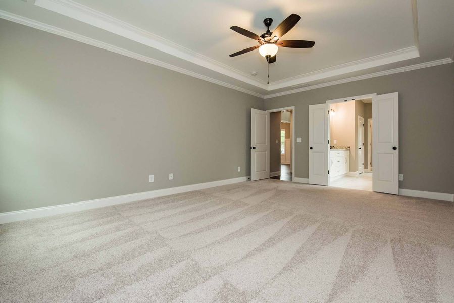 Empty bedroom with gray walls, light carpet, and open double doors.