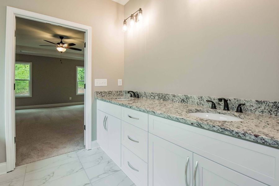 Bathroom with white vanity, granite countertop, and doorway to bedroom.