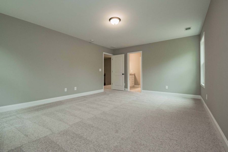 Empty bedroom with gray walls, carpet, and a white door.