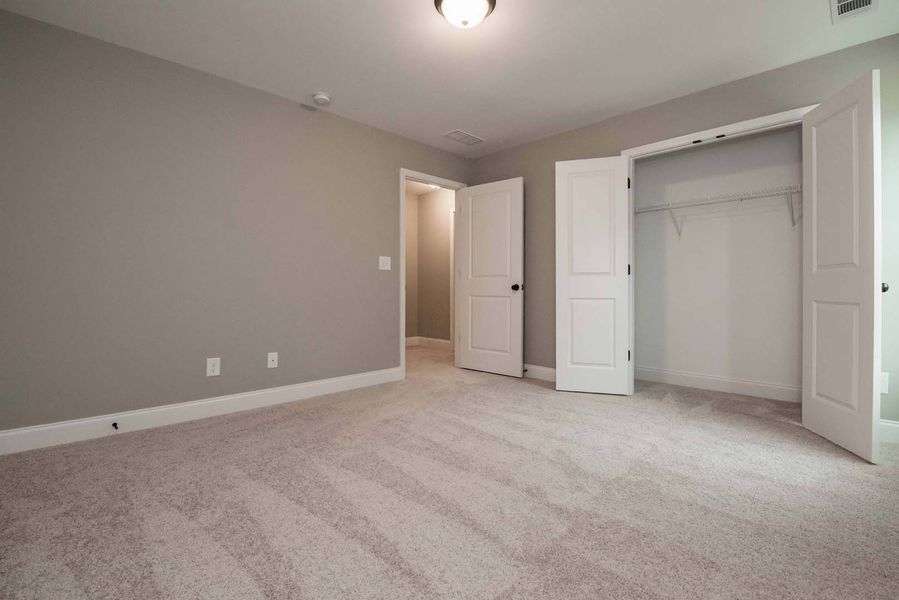 Empty bedroom with gray walls, white doors, closet, and beige carpet.