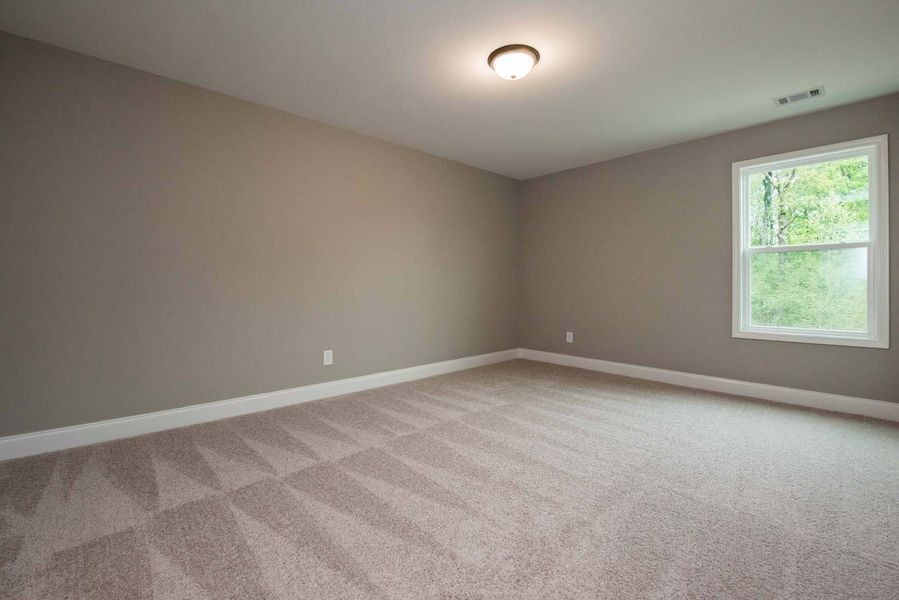 Empty room with beige walls, carpet, and a window.