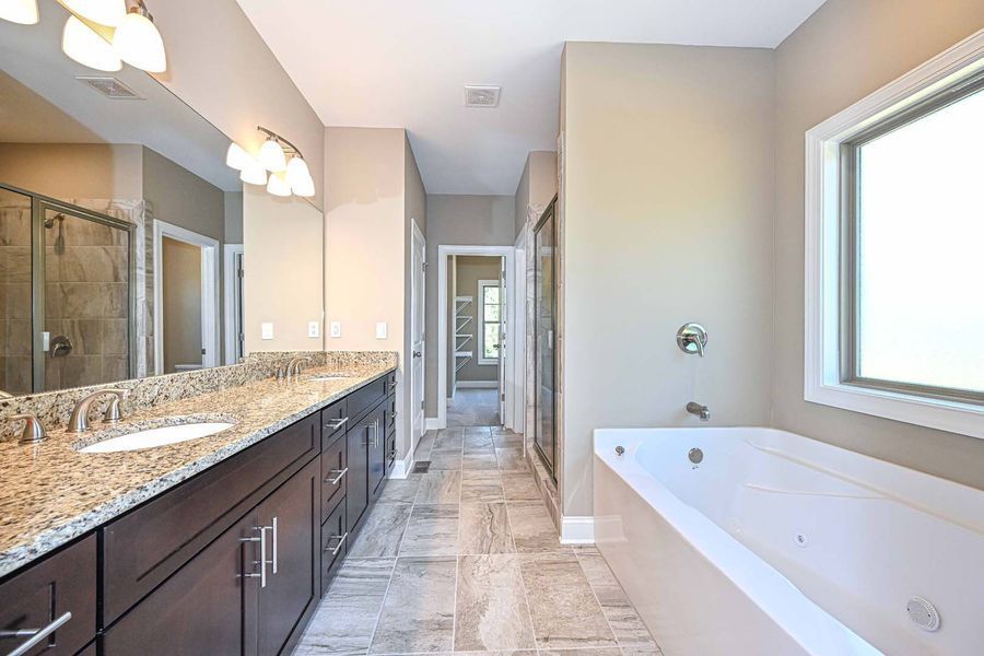 Spacious bathroom with a dual sink vanity, soaking tub, and a large window.